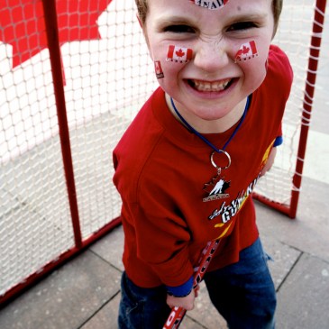 child smiling in front of a hockey net